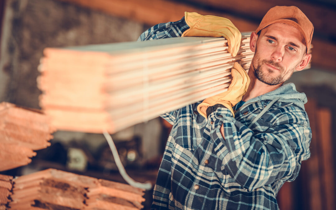 A young male contractor walks with wooden planks on his shoulder for under-deck-drainage-for-contractors blog.